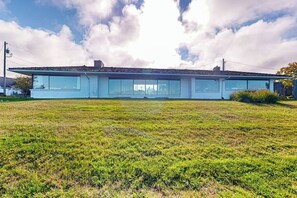 Una casa moderna con techo plano y ventanas amplias, rodeada por un campo cubierto de hierba.