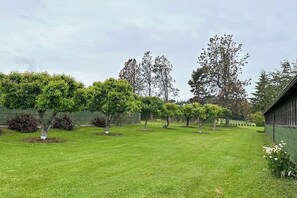 A well-maintained grassy area with trees and a building in the background.