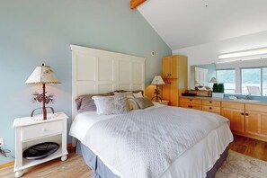 Ein Schlafzimmer mit einem großen Bett, Nachttischen, einem Kleiderschrank und einem Fenster.