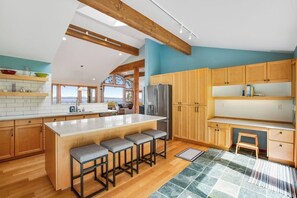 Una cocina moderna con armarios de madera, una isla central con taburetes de bar y vistas por la ventana.