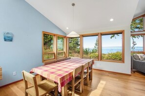 Un comedor con una mesa dispuesta para cuatro, ventanas amplias con vistas y una lámpara en el techo.
