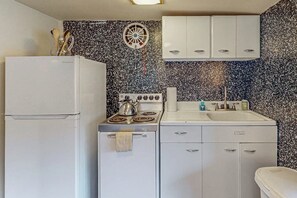 A compact kitchenette with a refrigerator, stove, sink, and cabinets. - 1BR Bayview Dog Friendly - Patio - Firepit - Washer Dryer (Gig Harbor)