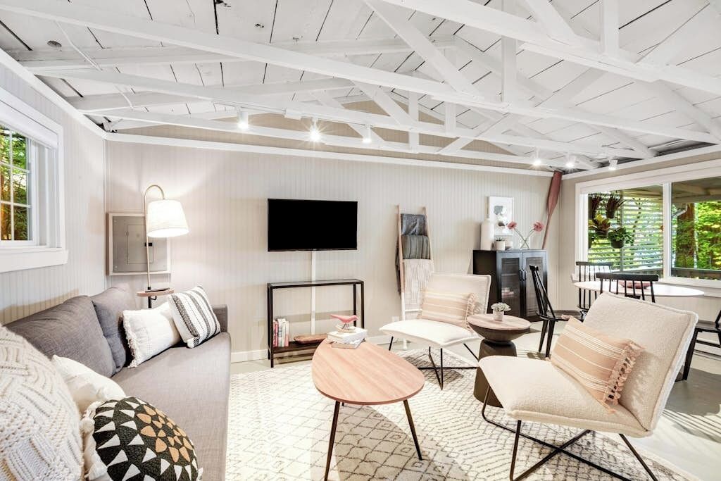 A modern living room with a sofa, armchairs, a coffee table, and a TV.