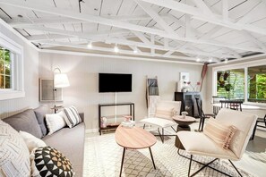 A modern living room with a sofa, armchairs, a coffee table, and a TV.