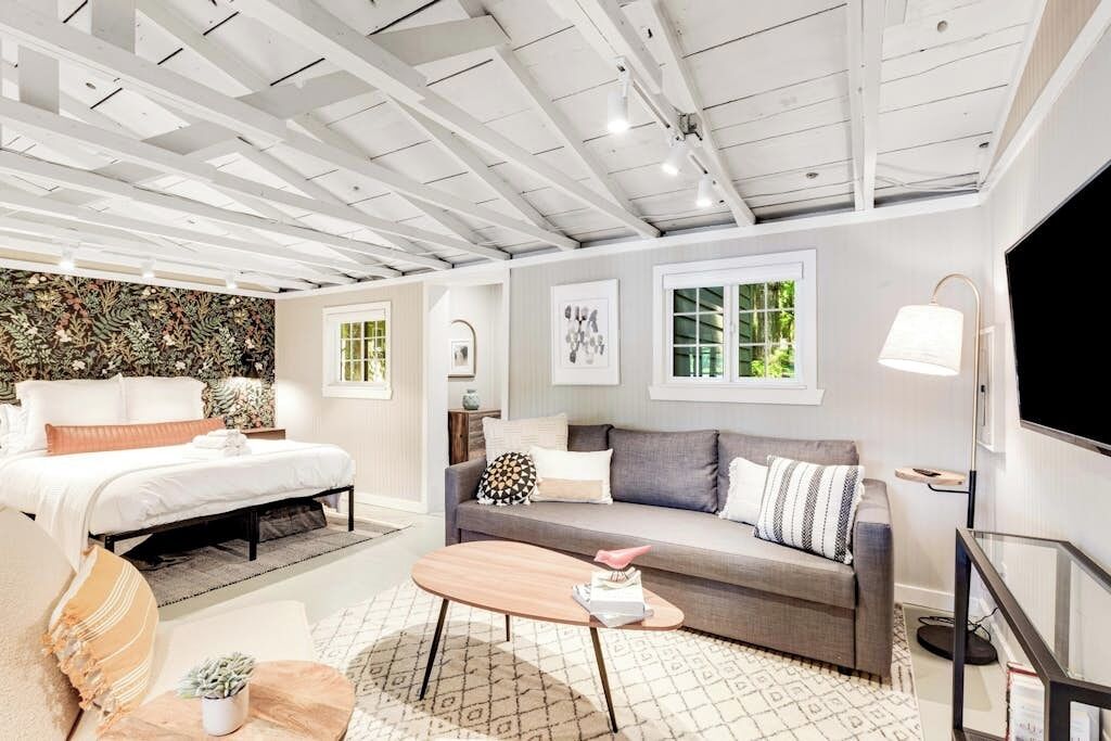 A modern living room with a bed, sofa, coffee table, and a TV.