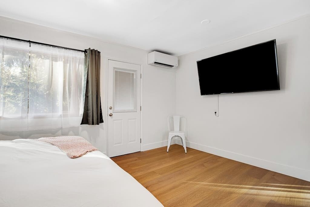Une pièce avec un lit, un téléviseur fixé au mur et une porte.