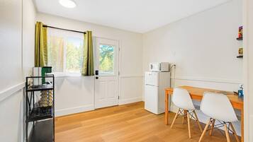Una cocina compacta con microondas, un refrigerador pequeño y una mesa de madera con dos sillas.