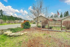 A historical society archival building with a sign, a flag, and a rural landscape. - Charming, dog-friendly 3BR with tennis and pickleball (Anderson Island)
