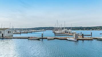 A marina with boats docked at piers, a small building on the left, and a calm water body.