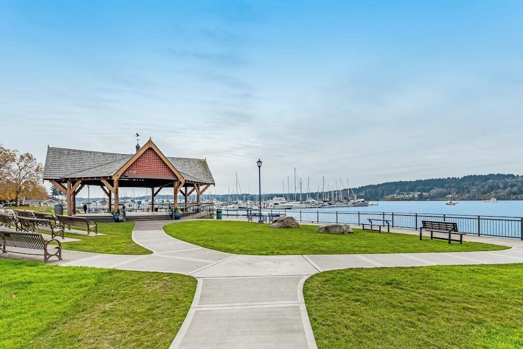 A waterfront park with a gazebo, benches, and a walking path.