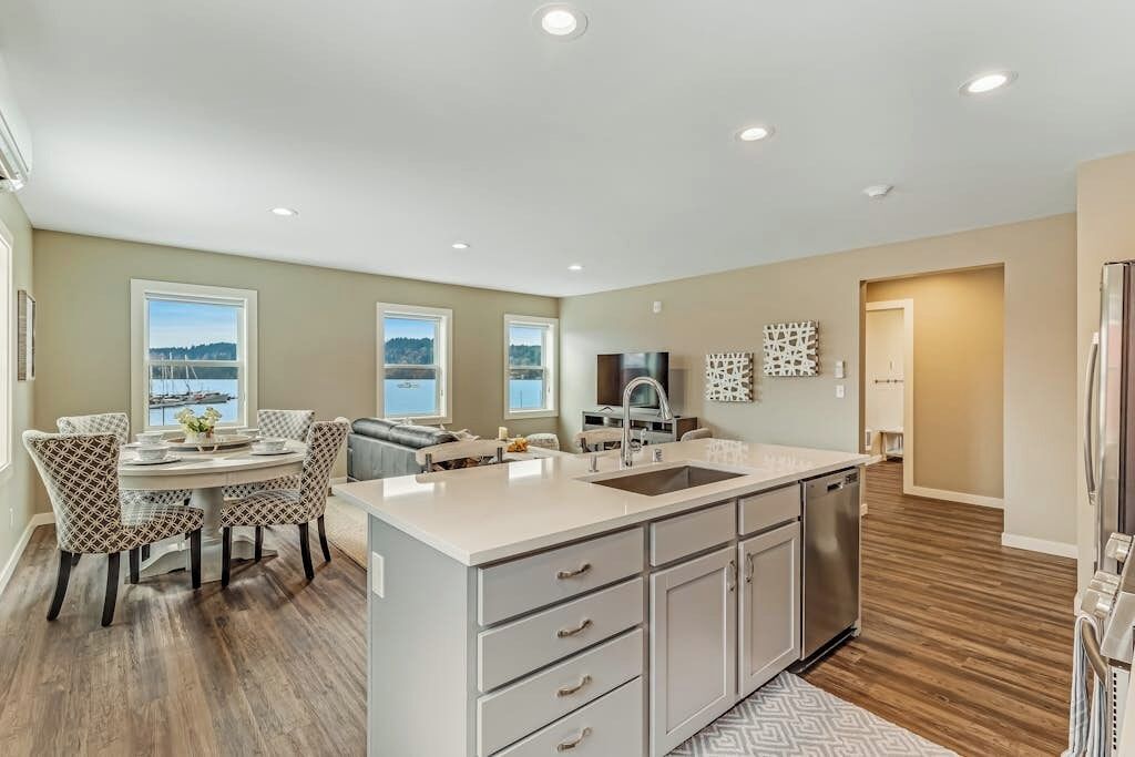 A modern kitchen with a central island, built-in appliances, and a dining area with patterned chairs.