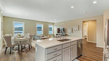 A modern kitchen with a central island, built-in appliances, and a dining area with patterned chairs.