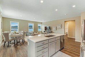 A modern kitchen with a central island, built-in appliances, and a dining area with patterned chairs.