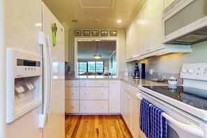 A kitchen with white cabinets, a refrigerator, an oven, and a microwave.