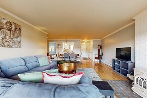A living room with a sofa, a coffee table, a TV, and a fireplace.