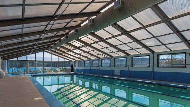 An indoor swimming pool with a glass ceiling, clear pool water, and a view of the outdoors. - 2 BR condo with stunning water views (Port Ludlow)