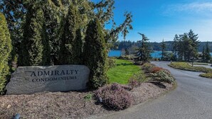 A sign for Admiralty Condominiums with a view of a lake and trees. - 2 BR condo with stunning water views (Port Ludlow)