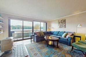 Un salon avec un canapé, une table basse et une vue dégagée grâce à de grandes fenêtres.