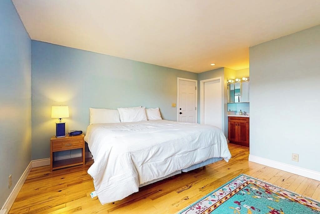 Une chambre à coucher avec un lit, une table de chevet, une lampe et un petit meuble.