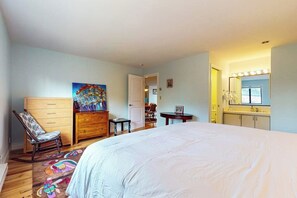 Une chambre à coucher avec un lit, une commode, une chaise et un tableau accroché au mur.