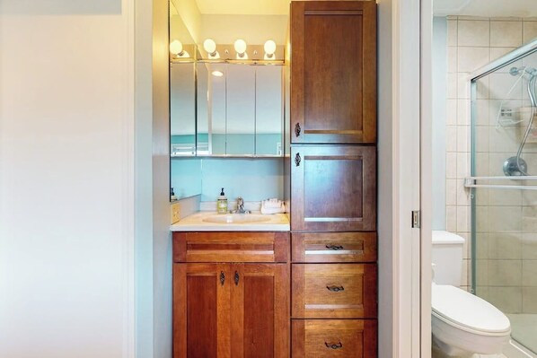 A bathroom with wooden cabinets, a sink, and a glass shower enclosure.
