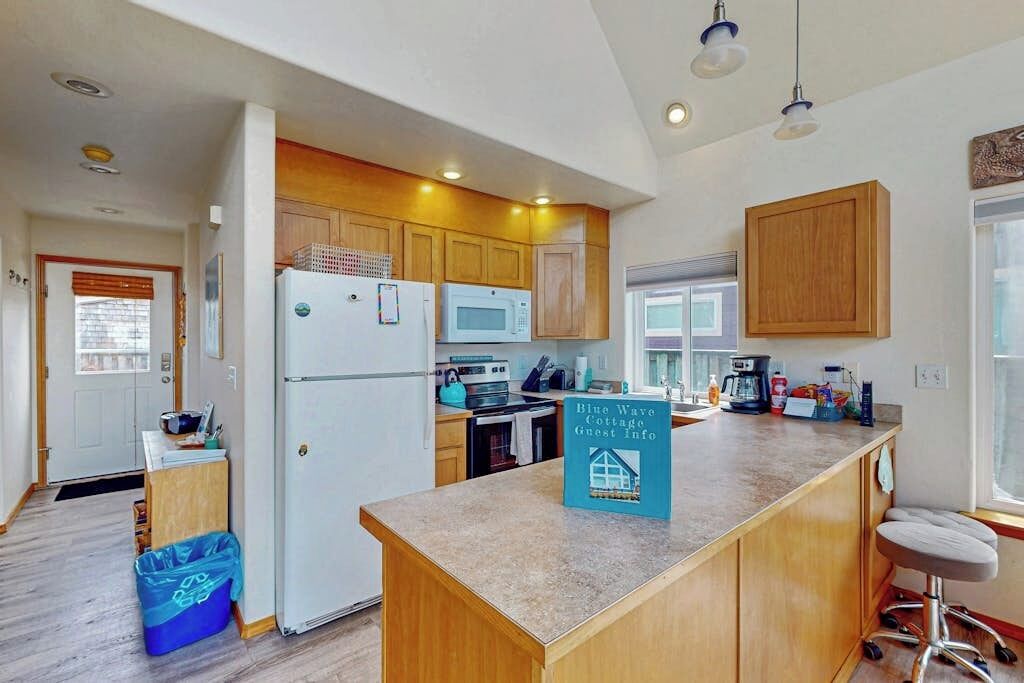 A modern kitchen with wooden cabinets, a central island, and a sign indicating guest information.