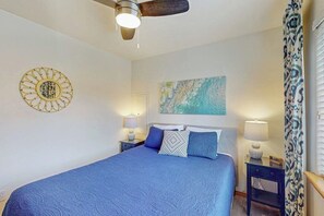 A bedroom with a bed, a ceiling fan, a wall art piece, and a nightstand with a lamp. - 2BR Oceanview Dog Friendly - Fireplace - Deck (Pacific Beach)