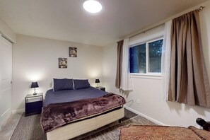 A bedroom with a bed, bedside tables, a window with curtains, and a wall-mounted artwork. - Charming 3BR - Hot Tub - Gas Grill - Dogs-OK (Port Orchard)