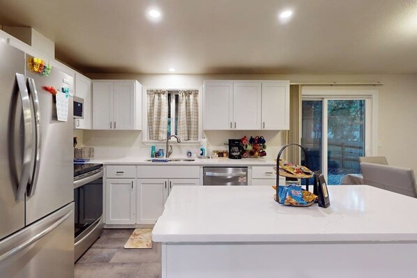 A modern kitchen with white cabinetry, stainless steel appliances, and a central island. - Charming 3BR - Hot Tub - Gas Grill - Dogs-OK (Port Orchard)