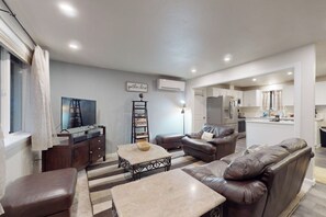 A modern living room with a sofa, coffee table, and a television. - Charming 3BR - Hot Tub - Gas Grill - Dogs-OK (Port Orchard)