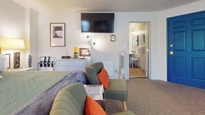 Una habitación de hotel con una cama, un escritorio, una silla, un televisor y una puerta azul.