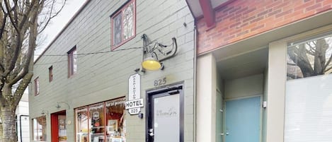 A two-story building with a sign indicating it is a hotel. There are windows on the ground floor, and a door with a sign above it.