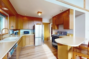 A modern kitchen with wooden cabinets, stainless steel appliances, and a central island. - 1BR  with loft retreat with wrap around balcony & Washer Dryer (Westport)