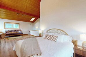 A bedroom with a large bed, a sofa, a wooden ceiling, and a window. - 1BR  with loft retreat with wrap around balcony & Washer Dryer (Westport)