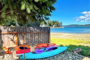 Ein Holzzaun mit angestückten Kajaks und einem Stand-Up-Paddleboard.