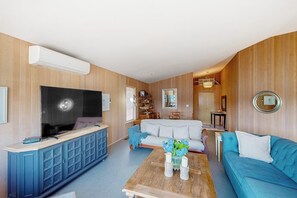 Ein Wohnzimmer mit Fernseher, Sofa, Couchtisch und Bücherregal.