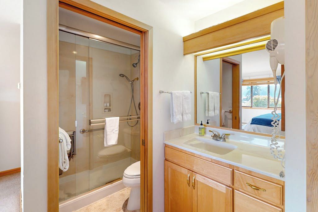 A bathroom with a glass-enclosed shower, a toilet, and a vanity with a mirror and sink.