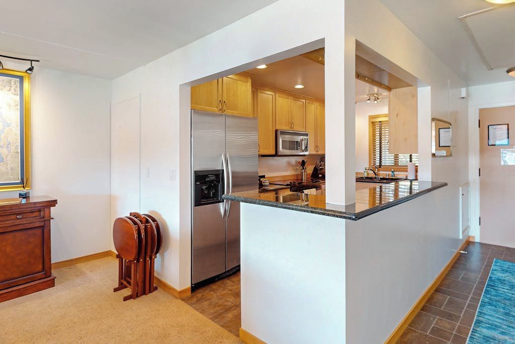 A modern kitchen with a central island, stainless steel appliances, and wooden cabinetry.