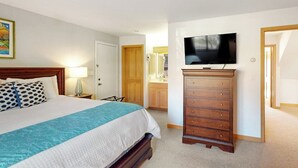 Ein Hotelzimmer mit einem Bett, einem Schminktisch, einem Fernseher und einer Tür zu einem Badezimmer.