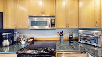 A kitchen with wooden cabinets, a stainless steel microwave, a gas stove, a coffee maker, and a toaster oven.