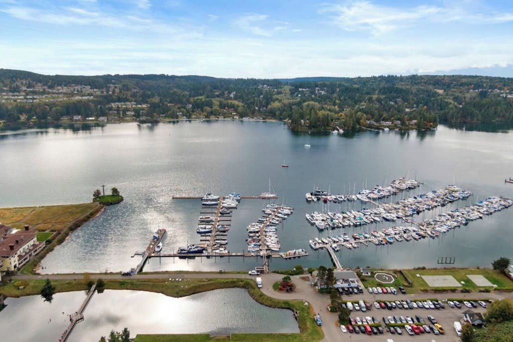 A marina with boats docked, a parking area, and a bridge connecting to the land.