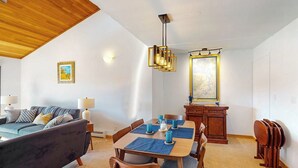 Ein Wohnzimmer mit einer Couch, einem Esstisch, Stühlen und einer Holzbalkendecke.