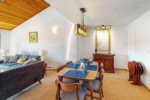 Ein Wohnzimmer mit einer Couch, einem Esstisch, Stühlen und einer Holzbalkendecke.