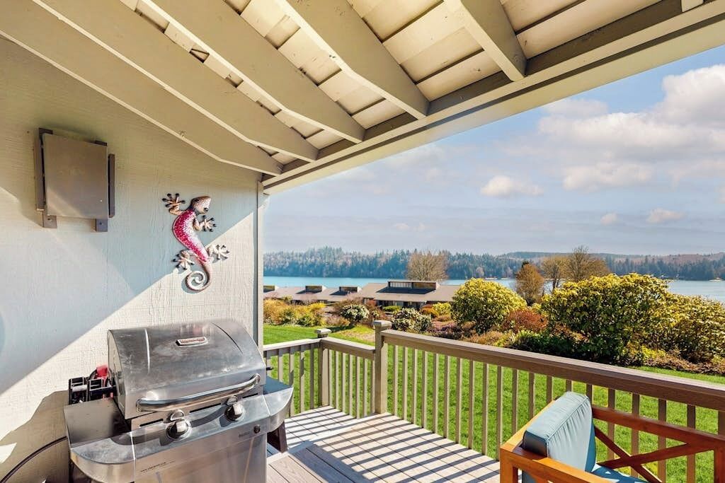 Un balcón con una parrilla, un caballito de mar decorativo y vistas a un lago y edificios.