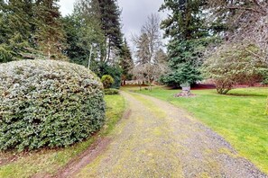 Un sentier de jardin qui traverse un espace paysager agrémenté de divers arbres et arbustes.