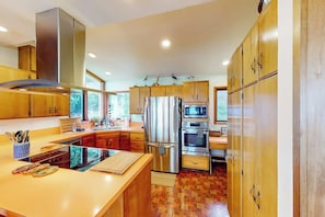 A modern kitchen with stainless steel appliances, wooden cabinets, and a central island. - Bayfront 1BR with patio, beach access, & views (Vashon)