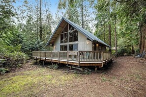 Eine Hütte mit einer Veranda, umgeben von Wald.