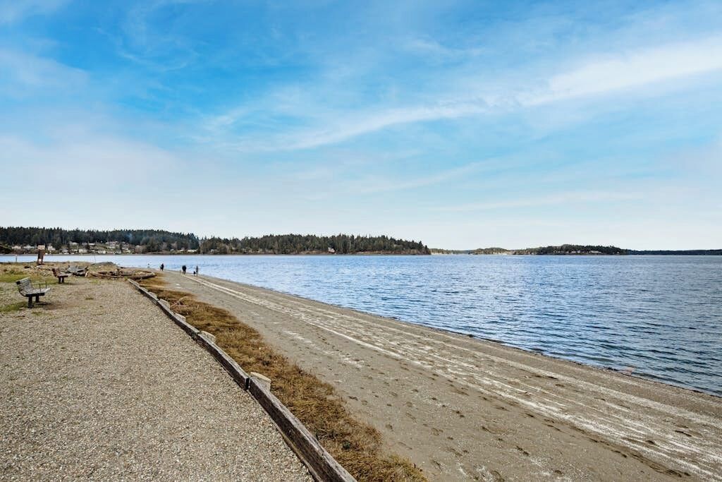 A gravel path beside a calm lake with a distant forested island.