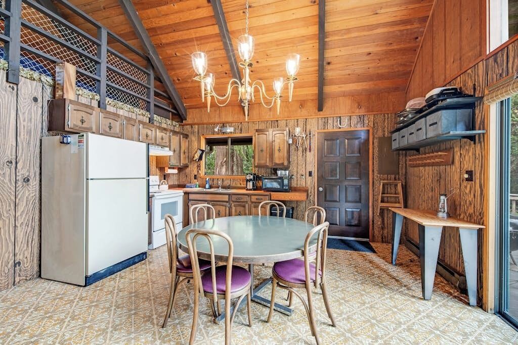 Ein Holzinterieur mit Esstisch, Stühlen, einem Kühlschrank und einer Küchenzeile.