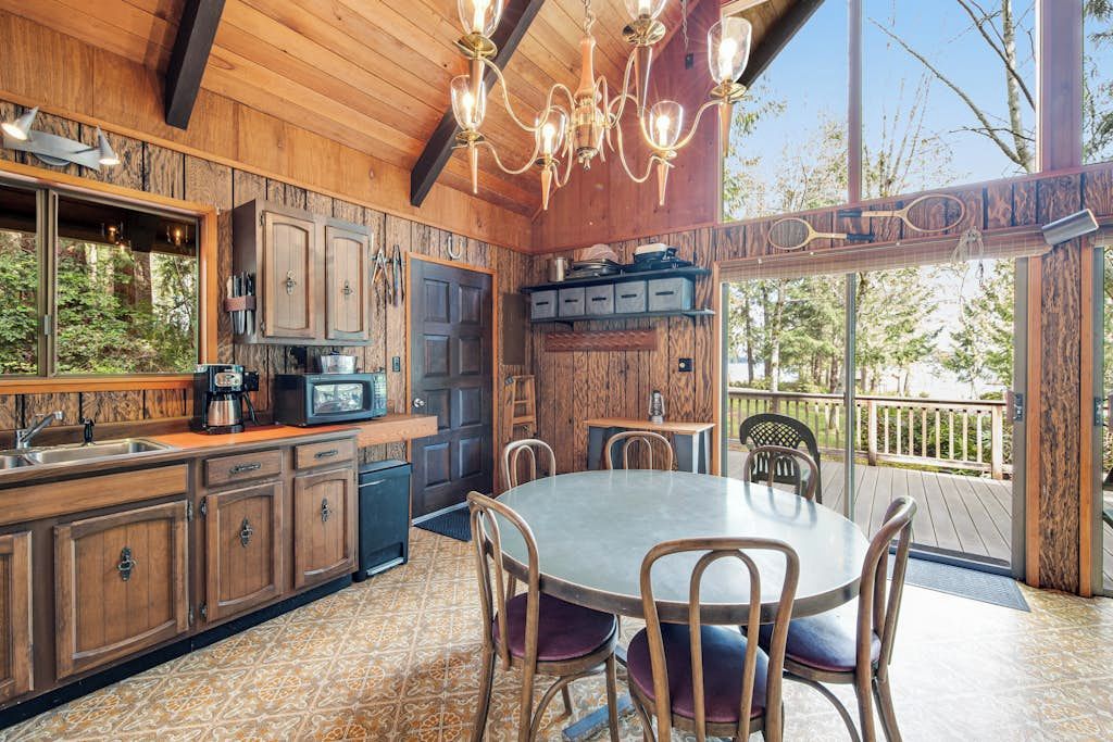 Een houten interieur met een eethoek, keuken en grote ramen.